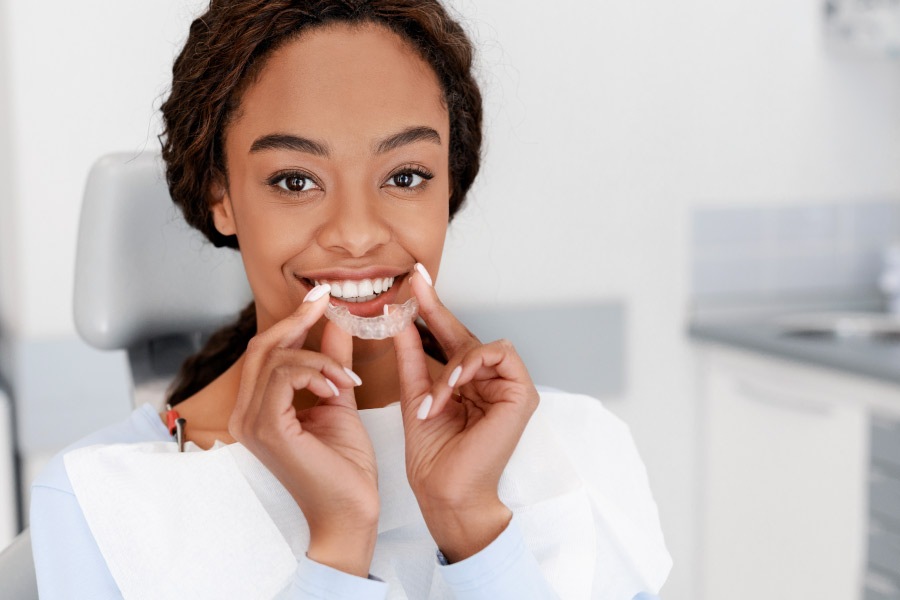 Pretty black young woman holding a clear aligner