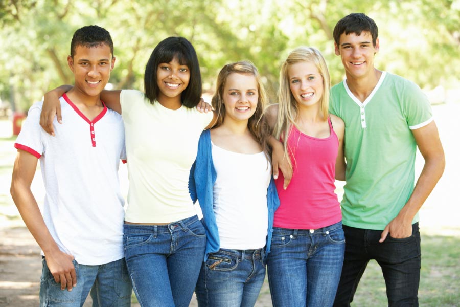 Five smiling teenagers with straightened teeth standing together