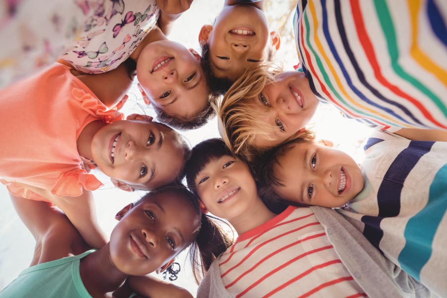 Circle of multiracial kids with heads together looking down.
