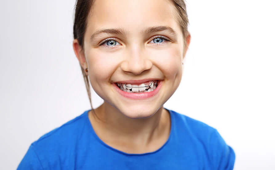 smiling girl wearing a retainer on her teeth