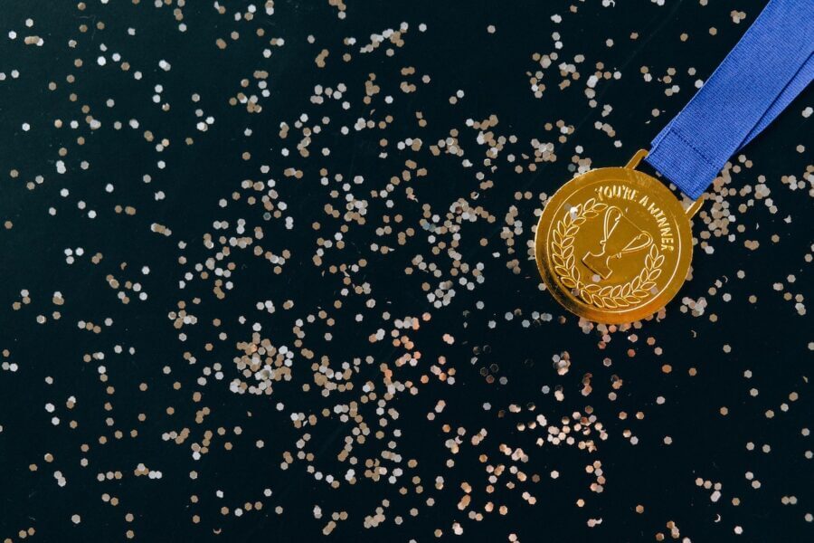 Aerial view of a gold medal that says "you're a winner" on a dark background covered with glittery confetti