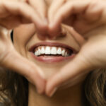 Closeup of a woman holding her hands in a heart in front of her teeth