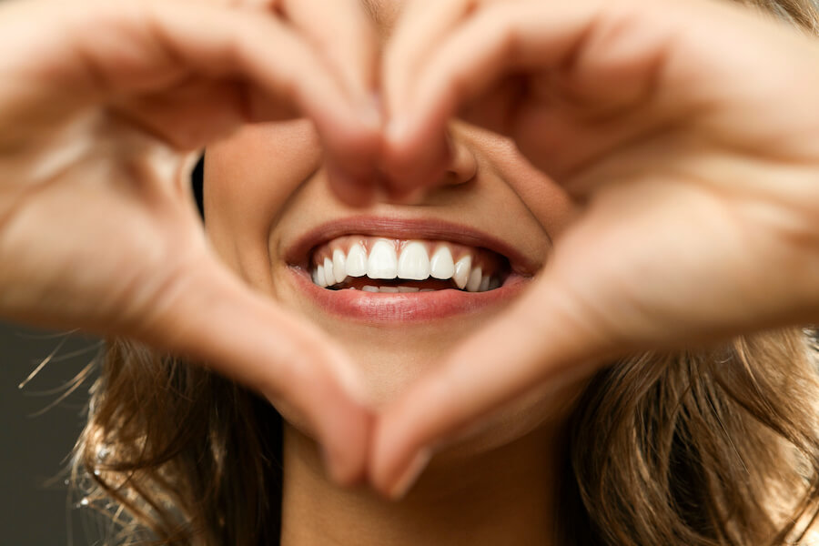 Closeup of a woman holding her hands in a heart in front of her teeth