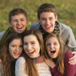 Coed group of teens smiling outside, some wearing braces